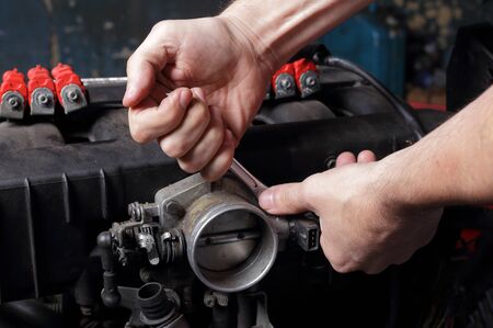 Car service - Engine repair, mechanic hands with wrench unscrews fuel system nutの写真素材