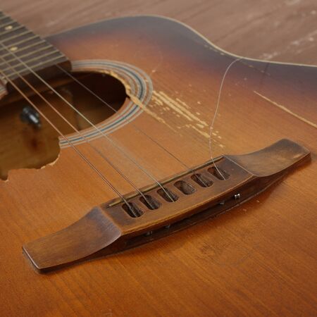 Musical instrument - Closeup fragment broken classic acoustic guitar on a wooden background.