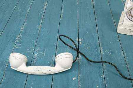Closeup White vintage phone with the picked-up on a retro old blue wood textured plank backgroundの写真素材