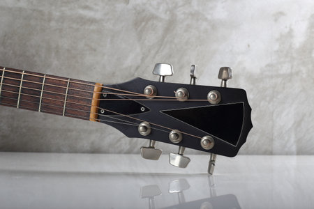 Musical instrument - headstock peghead neck tuning peg acoustic guitar background of a concrete wall...