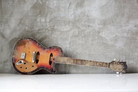 Musical instrument - Old, dirty, broken electric guitar concrete wall backgroundの写真素材