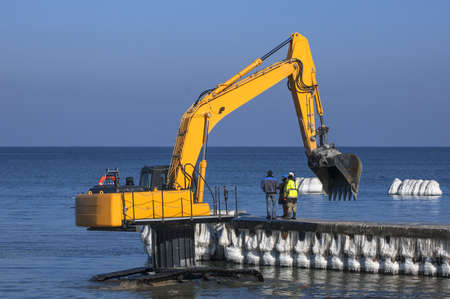 EXCAVATOR ON THE SEA SHORE - COUNCIL WORCERS