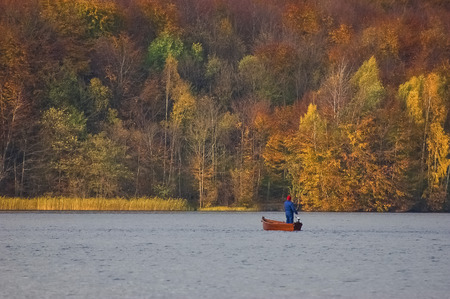ANGLER ON THE LAKE. Autumn landscape and fisherman in a boat on the lake.の写真素材