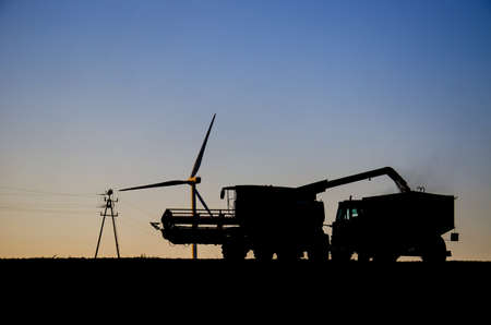 HARVEST ABOUT SUNSET. Farm equipment in a field at sunset at harvest time.