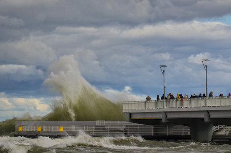 KOLOBRZEG, WEST POMERANIA / POLAND: Stormy weather on the Polish coast in Kolobrzeg. People watching the storm waves breaking on the pierのeditorial素材