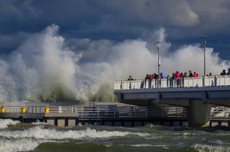 KOLOBRZEG, WEST POMERANIA / POLAND: Stormy weather on the Polish coast in Kolobrzeg. People watching the storm waves breaking on the pierのeditorial素材