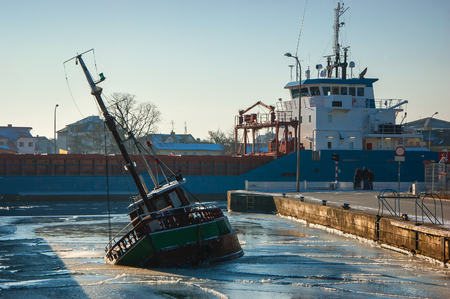 SINK BOAT IN THE HARBOR. The ship Enters a port near the sinking boatの写真素材
