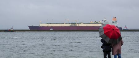 LNG TANKER IN THE PORT - people are watching the big mooring a vessel to the wharfの写真素材