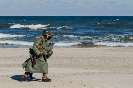 KOLOBRZEG, WEST POMERANIAN / POLAND - 2018: Reconstruction of battle for Ko?obrzeg - Reconstruction group in uniforms of Wehrmacht marches on the sea beachのeditorial素材