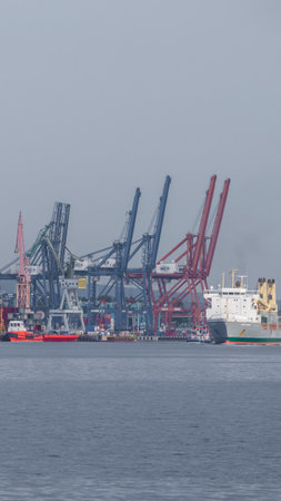 GDYNIA, POMERANIA REGION / POLAND - 2018: Harbor cranes and the ship sailing on the sea