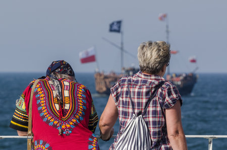 KOLOBRZEG, WEST POMERANIAN / POLAND - 2018: Holidaymakers on pier and a walking shipのeditorial素材