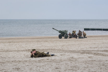 KOLOBRZEG, WEST POMERANIAN / POLAND - 2019: Reconstruction of battle for Kolobrzeg - Observer, artillery crew and cannon of the Polish Army on sea beachのeditorial素材