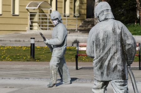 KARLINO, WEST POMERANIAN / POLAND - 2020: Figure of a fireman from a fountain in a city square in a protective mask against coronavirusのeditorial素材