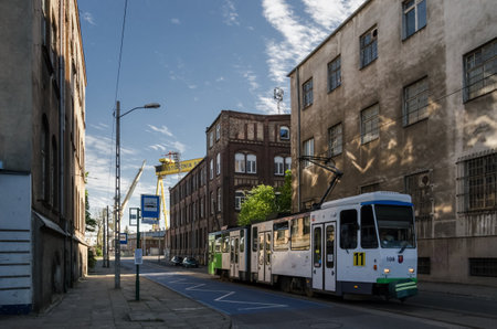 SZCZECIN, WEST POMERANIAN / POLAND - 2016: Tram at the stop between old industrial buildingsのeditorial素材