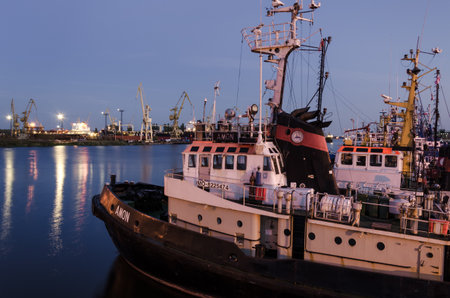 SZCZECIN, WEST POMERANIAN / POLAND - 2020: Tugs tucked to the port quays against the background of shipyard docksのeditorial素材