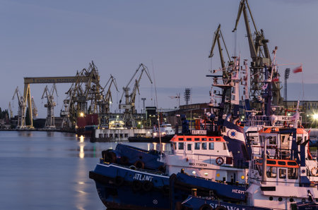 SZCZECIN, WEST POMERANIAN / POLAND - 2020: Tugs tucked to the port quays against the background of shipyard docksのeditorial素材