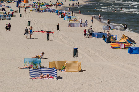 KOLOBRZEG, WEST POMERANIAN / POLAND - 2020: People relax on the sunny sea beach while maintaining safe distancesのeditorial素材