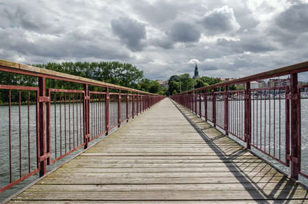 PIER - Pedestrian bridge over the water with a marina and a tourist town in backgroundの写真素材