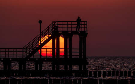 SUNSET - A man on the seashore observes a natural phenomenonの写真素材