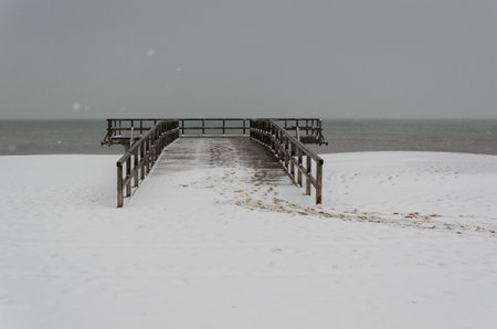 SEA COAST IN WINTER - Snowstorm over the beach and wooden pierの写真素材
