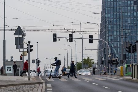POZNAN - POLAND - 2021: Pedestrians and a man on an electric scooter at a pedestrian crossingのeditorial素材