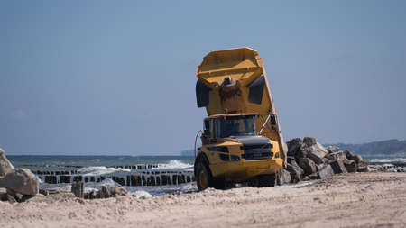 CONSTRUCTION DUMP TRUCK - A big vehicle carries boulders on the sea beachの写真素材