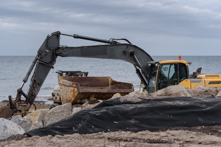 KOLOBRZEG, WEST POMERANIAN - POLAND - 2022: Excavator and construction dump truck on the sea coastのeditorial素材