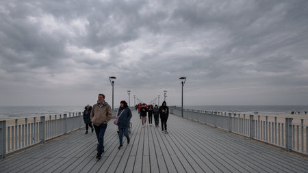 KOLOBRZEG, WEST POMERANIAN - POLAND - 2023: Tourists walk on a cloudy day by the sea on the pierのeditorial素材