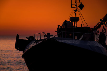 SUNSET BY THE SEA - Fishing boats on coast in the light of evening sunの写真素材