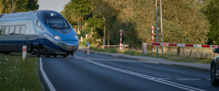 TYMIEN, WEST POMERANIAN - POLAND - JULY 15, 2023: An express train runs through a railroad crossing...