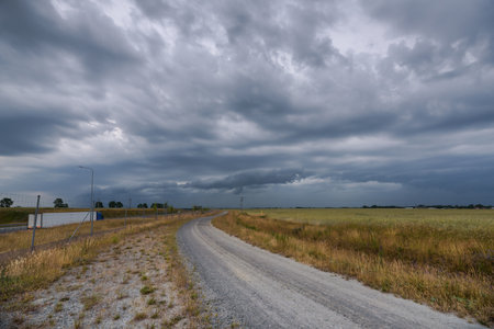 RAIN CLOUDS - Cloudy weather on dirt road and farmlandの写真素材