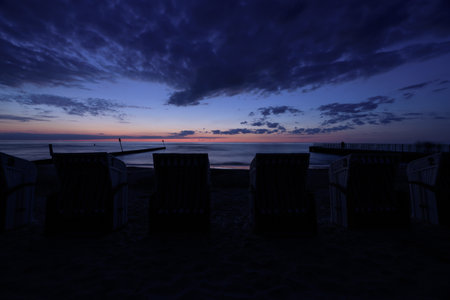 SUNSET OVER THE COAST - Romantic evening on the sea beach with beach baskets in the backgroundの写真素材