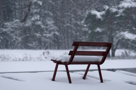 WINTER ATTACK - A bench and a fishing pier by the lake covered with snowの写真素材