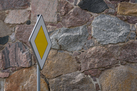 PRIORITY ROAD - Traffic sign against the background of a stone wallの写真素材
