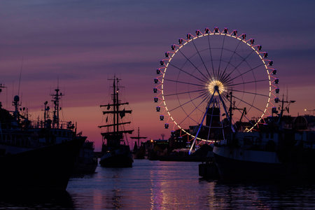 SEA PORT - A small tourist ship in harbor at dusk against background of ferris wheel