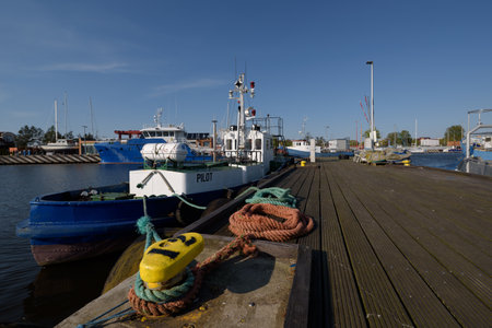 PILOT BOAT IN SEAPORT - Mooring lines on the bollard and a ship at the quayの写真素材