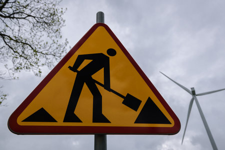 ROADWORKS AREA - Worning sign on the trees and wind mill background