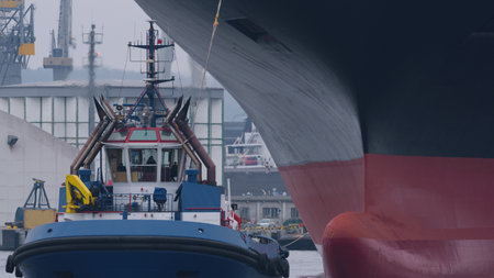 MARITIME TRANSPORT - A tugboat maneuvers with a ship in a seaport