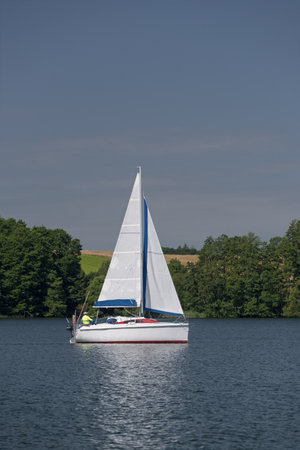 A sailboat with white sails on a lake