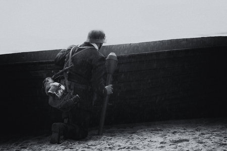 GERMAN IN BLACK UNIFORM - A World War II soldier with a panzerfaust hides behind a boatの写真素材