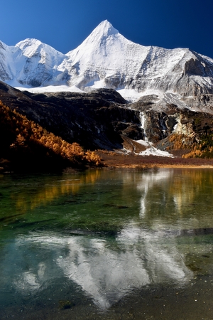 Sacred mountain Jambeyang (5,958m) with blue sky background and its reflection on icy clean lake. This place is supposed to be the real Shangrila. Daocheng Yading Nature Reserve, Sichuan, China.の写真素材