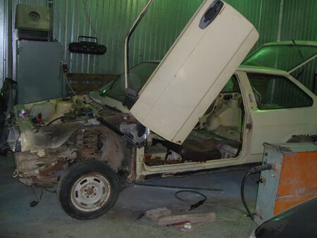 The dismantled car stands at the service station with the engine disassembled and the doors open up, the door converted like a sports car.の写真素材