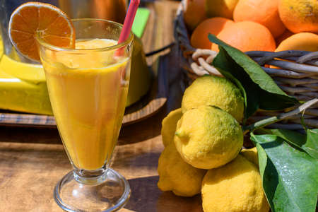 Freshly squeezed orange juice in a glass cup, next to the table lies oranges and lemons.