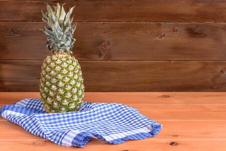 Ripe anans lay on a blue pololotentsa on a wooden table and a wooden background.の写真素材