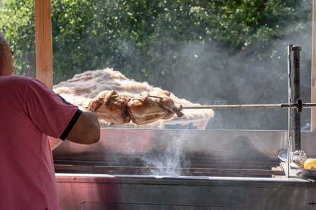 The cook prepares a chicken on a spit with fragrant smoke.の写真素材