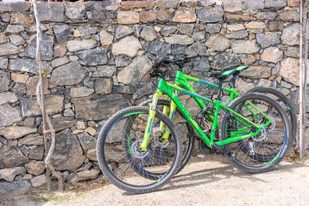 Two bicycles stand near the stone wall.の写真素材