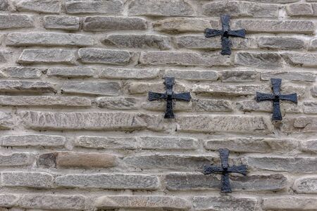 Iron cross hanging on a stone wall, background.の写真素材