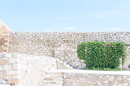 Stone wall and blue sky with clouds, background free space for text.の写真素材
