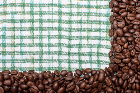 Texture of a colored towel, a towel of a cellular type, on which lies a certain amount of brown coffee beans. Top view with a bunch of coffee beans with space for text.の写真素材