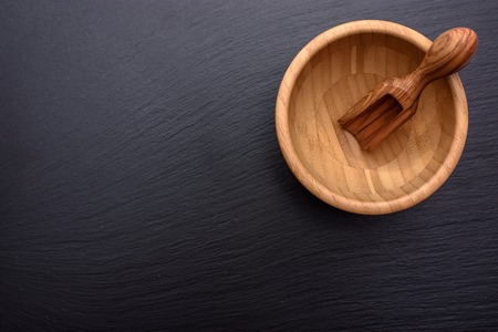 A scoop of olive tree lies in a wooden cup on the background of a black shale stone.の写真素材